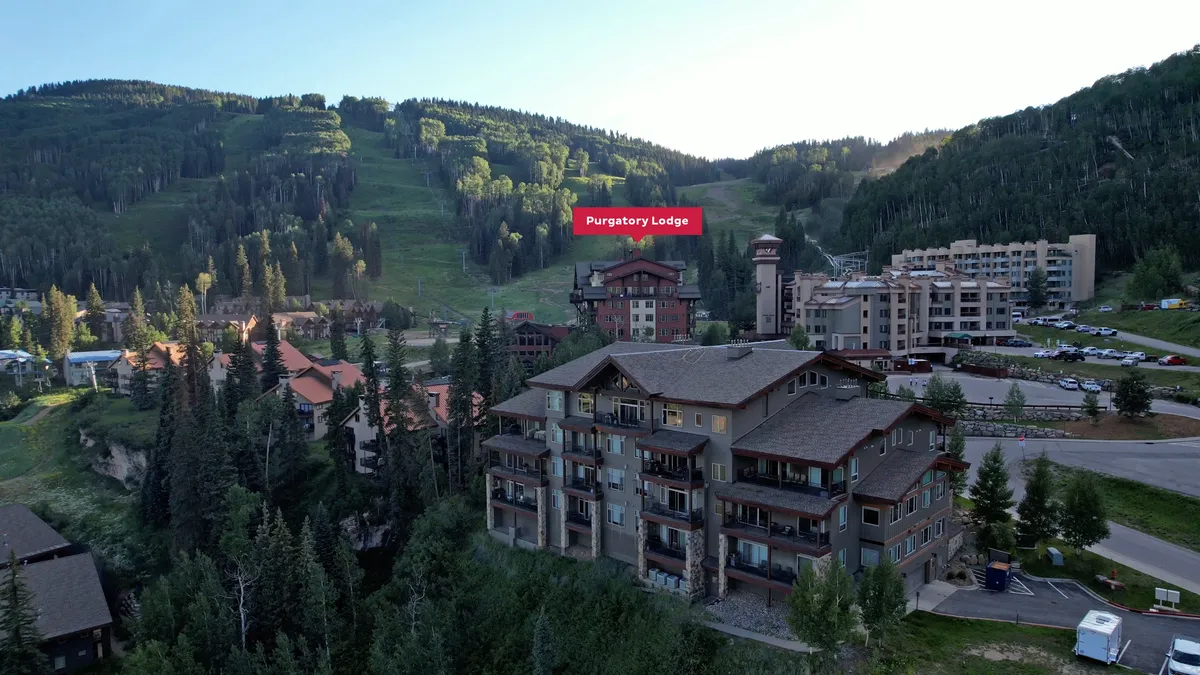 This exterior image captures Purgatory Lodge with its surrounding mountains and a visible parking area, providing a sense of arrival and immediate access to the heart of the ski village. The lodge’s prominent placement emphasizes its role as the base for adventure, with the parking area subtly suggesting heated garage access.