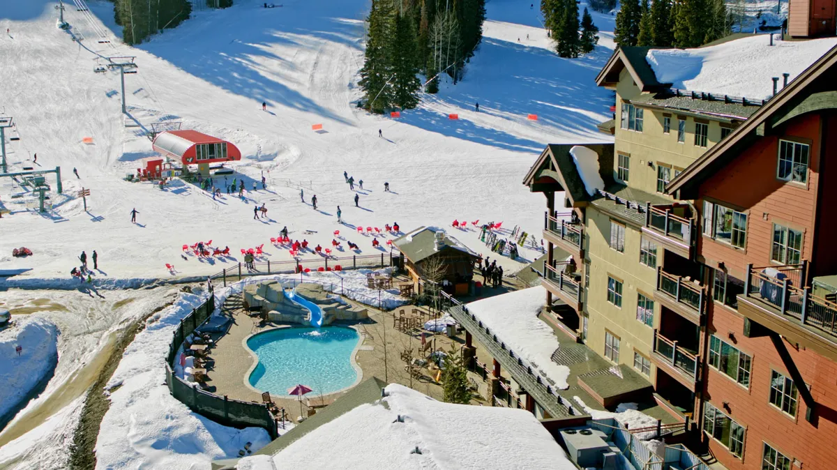 An energetic exterior shot that captures the property’s proximity to ski slopes, the outdoor swimming pool, a ski lift, and plentiful seating. The image buzzes with activity, showing both winter and summer fun—ideal for families looking for adventure and relaxation in one place.