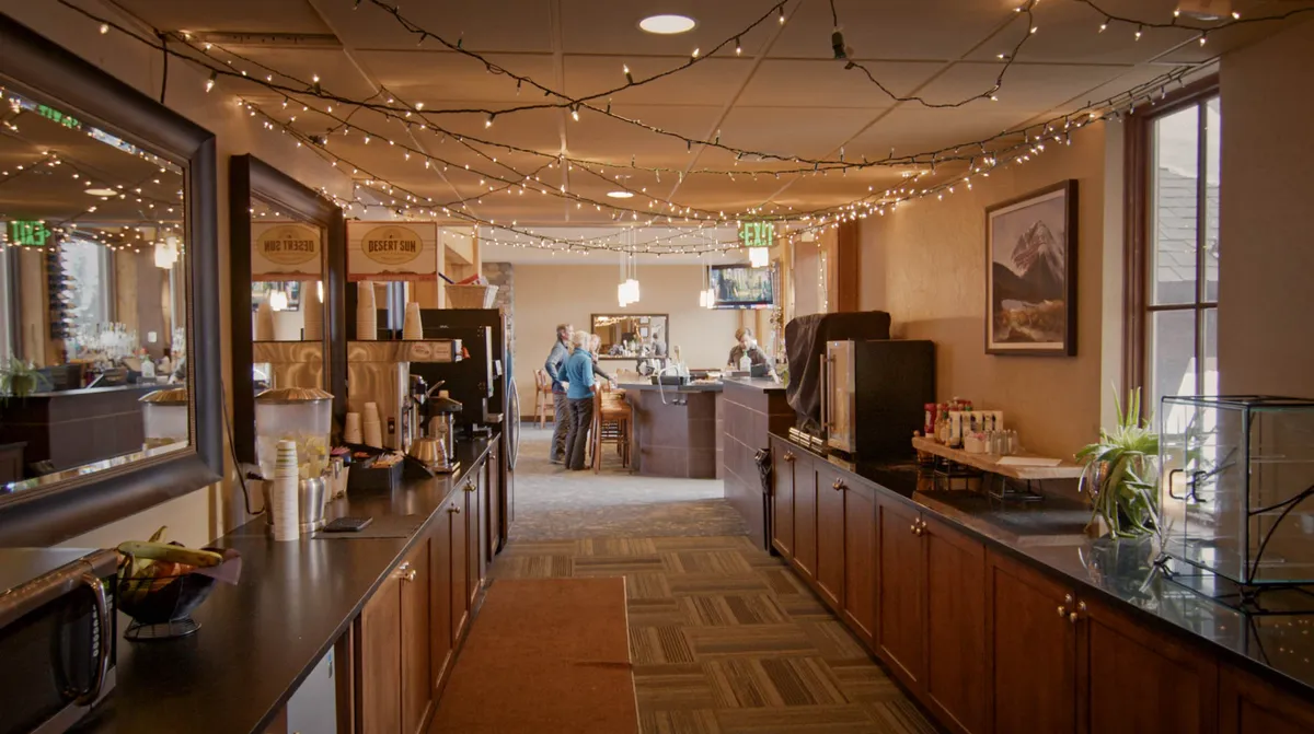 This image features a cozy coffee station and bar area, enhanced by decorative lighting and mountain-themed artwork. The scene suggests a welcoming spot for casual gatherings or enjoying a quiet coffee break, with hints of mountain ambiance in the decor.