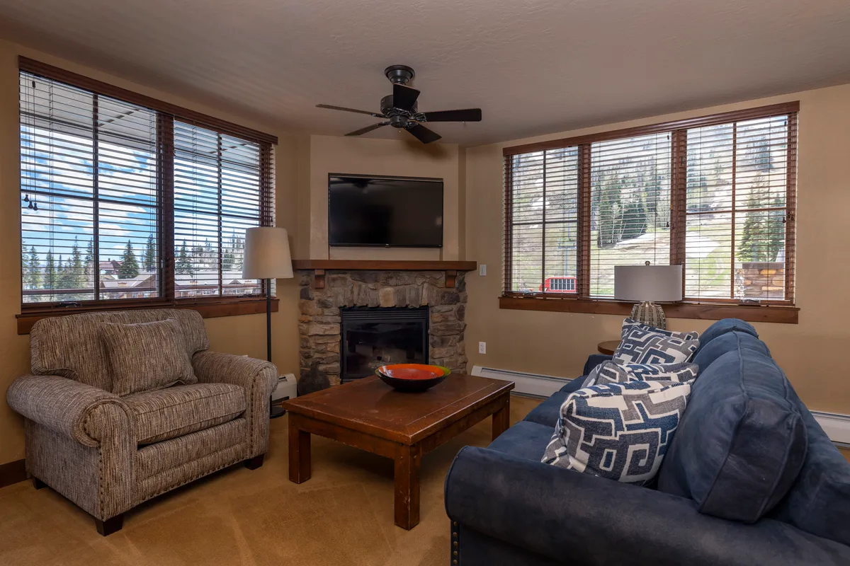 A warm lounge area with plush sofas, a crackling fireplace, and expansive windows offering glimpses of the outdoors. The space feels inviting and is well-suited for relaxing with a book, socializing with friends, or watching the snowfall, aligning with the tranquil and refined retreat described in the section.